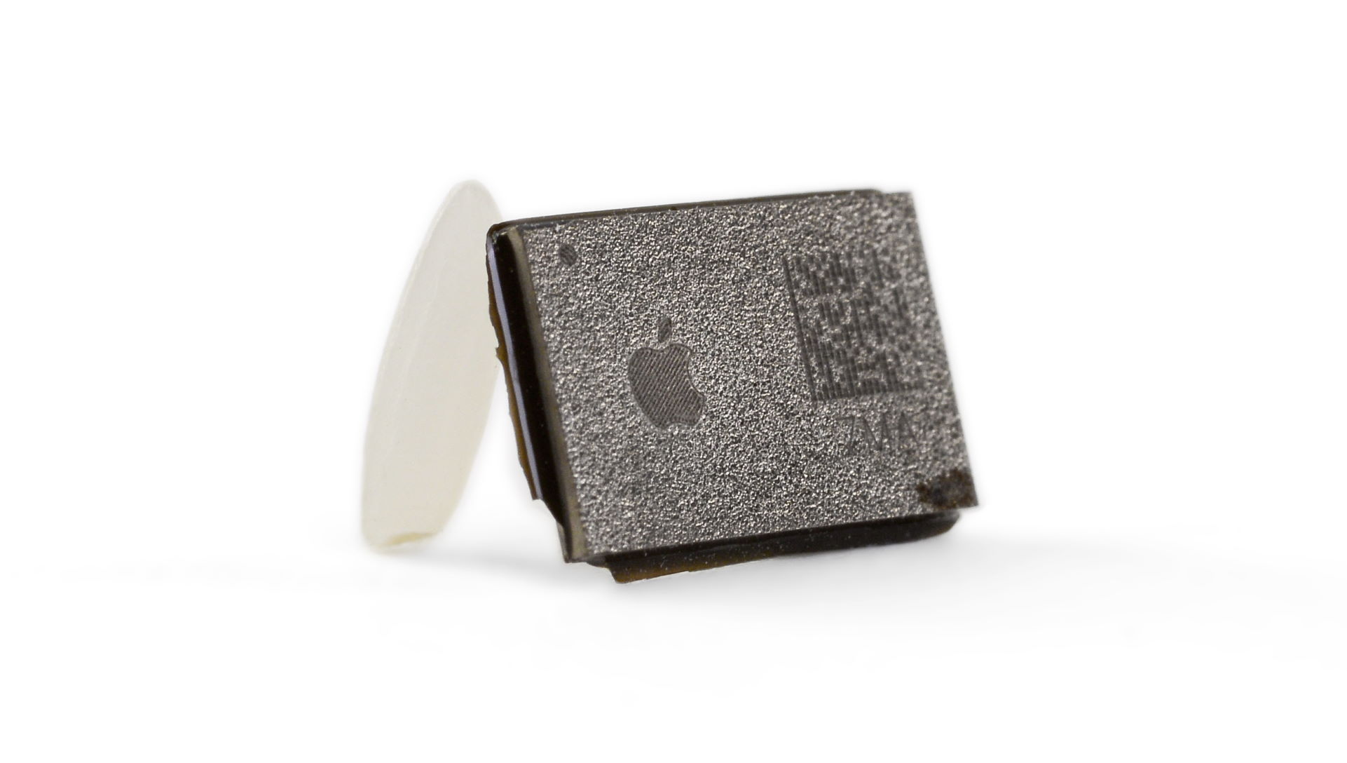 A microcontroller with Apple branding leant up against a grain of rice for scale