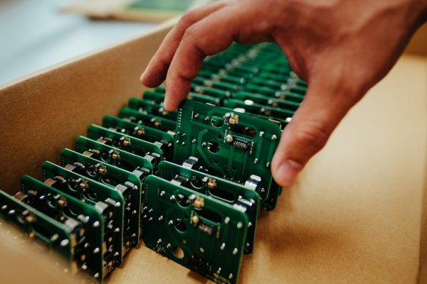 Hand pulling a small circuit board from a box